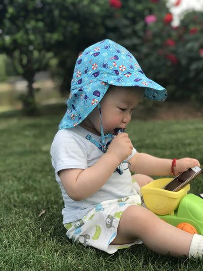bébé jouant dans herbe avec sa casquette enfant
